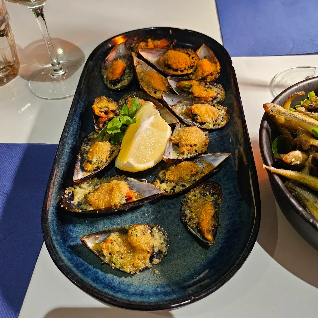 Moules gratinées servies sur une assiette bleue